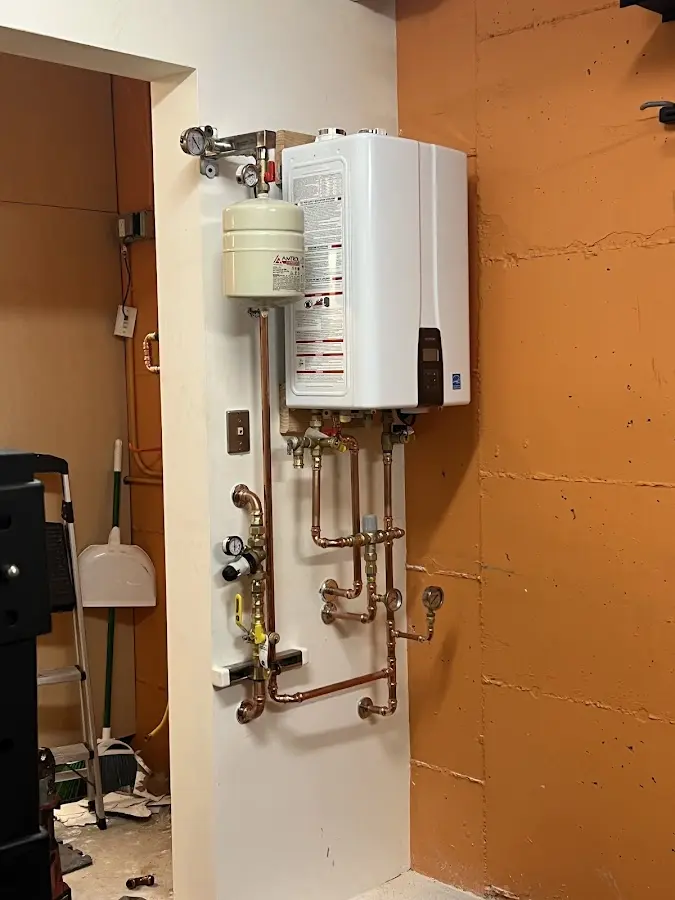 Plumbing technician inspecting water heater connections in White
